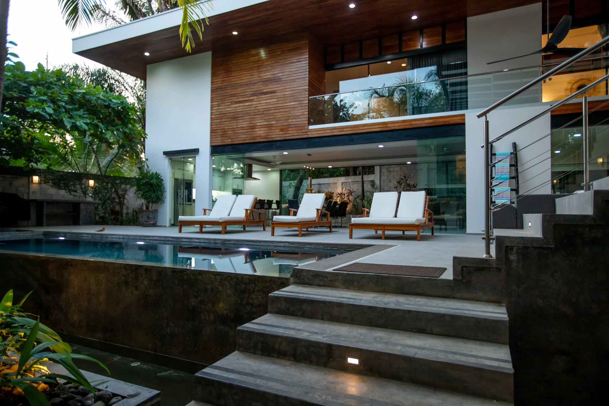 Casa Almendra villa exterior at night with pool, sun loungers, and lit architecture, Playa Guiones Nosara, Costa Rica