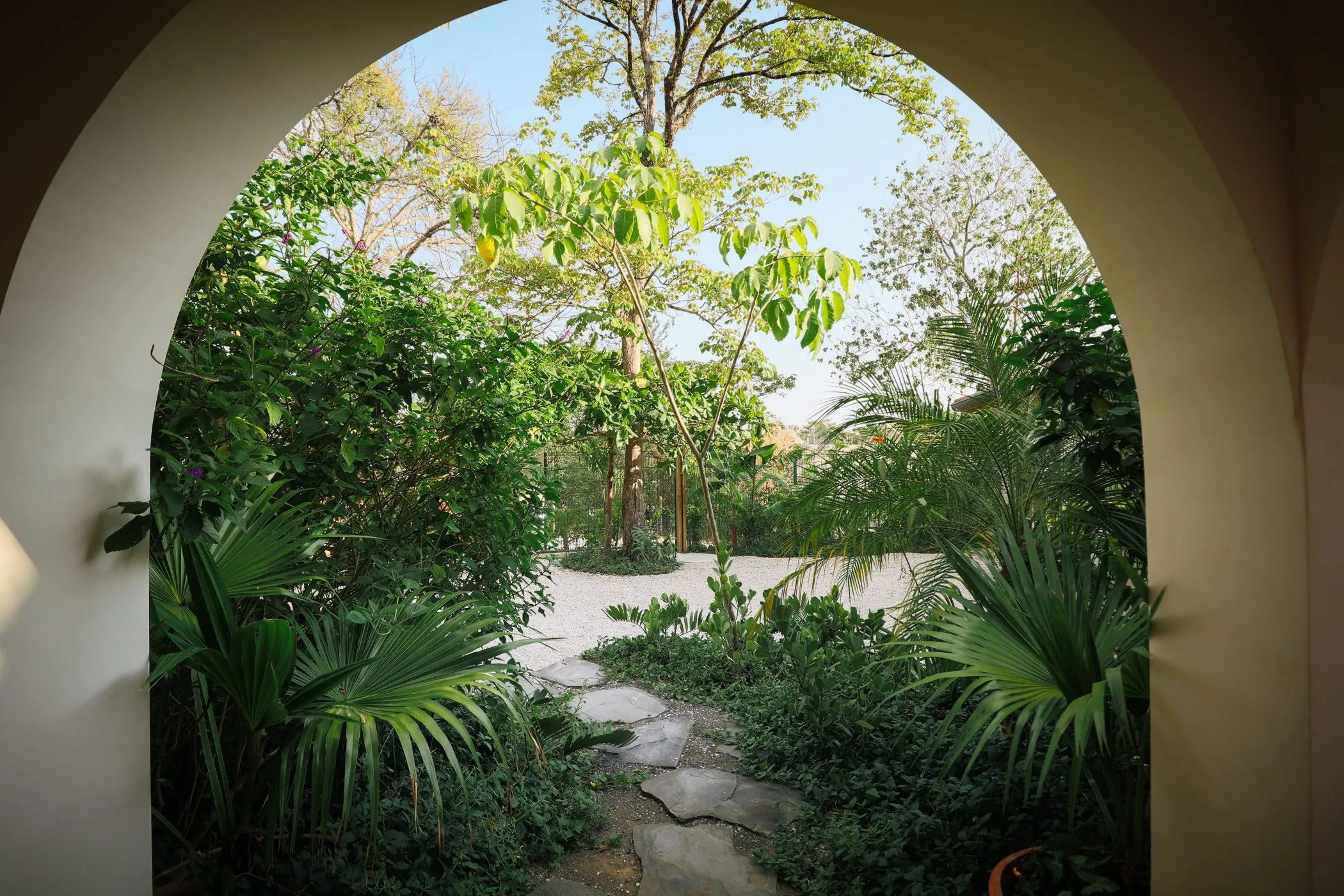 Casa Oceanus villa garden archway framing a palm tree, Nosara