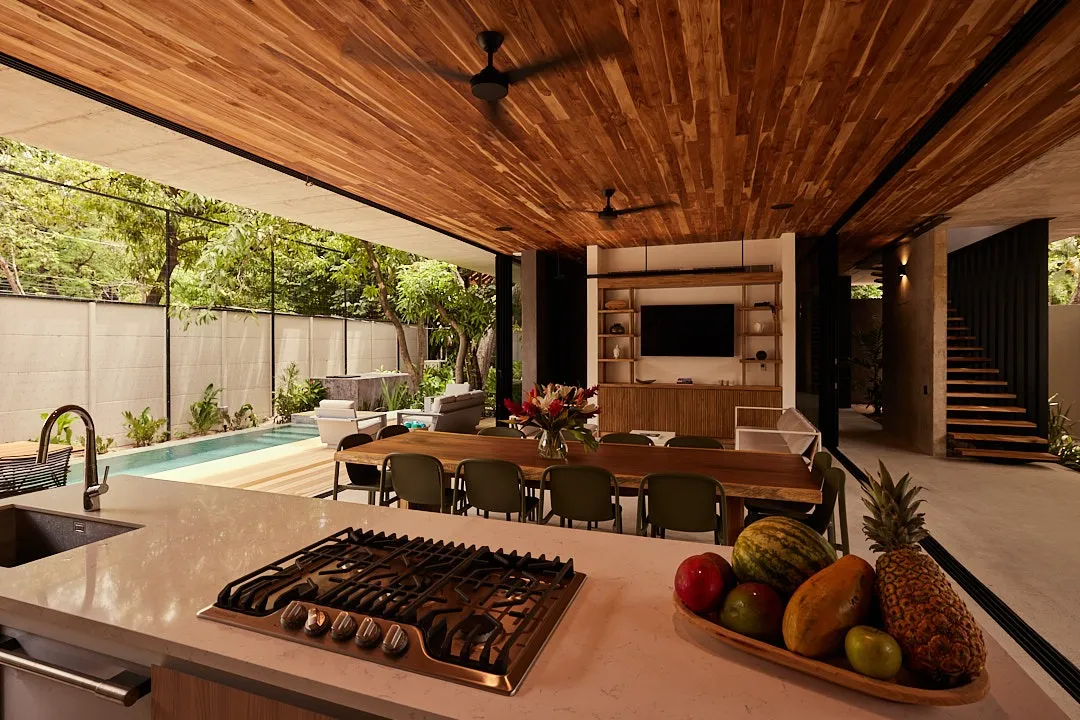Calma House villa dining area with open kitchen island and sliding glass to the pool, Nosara