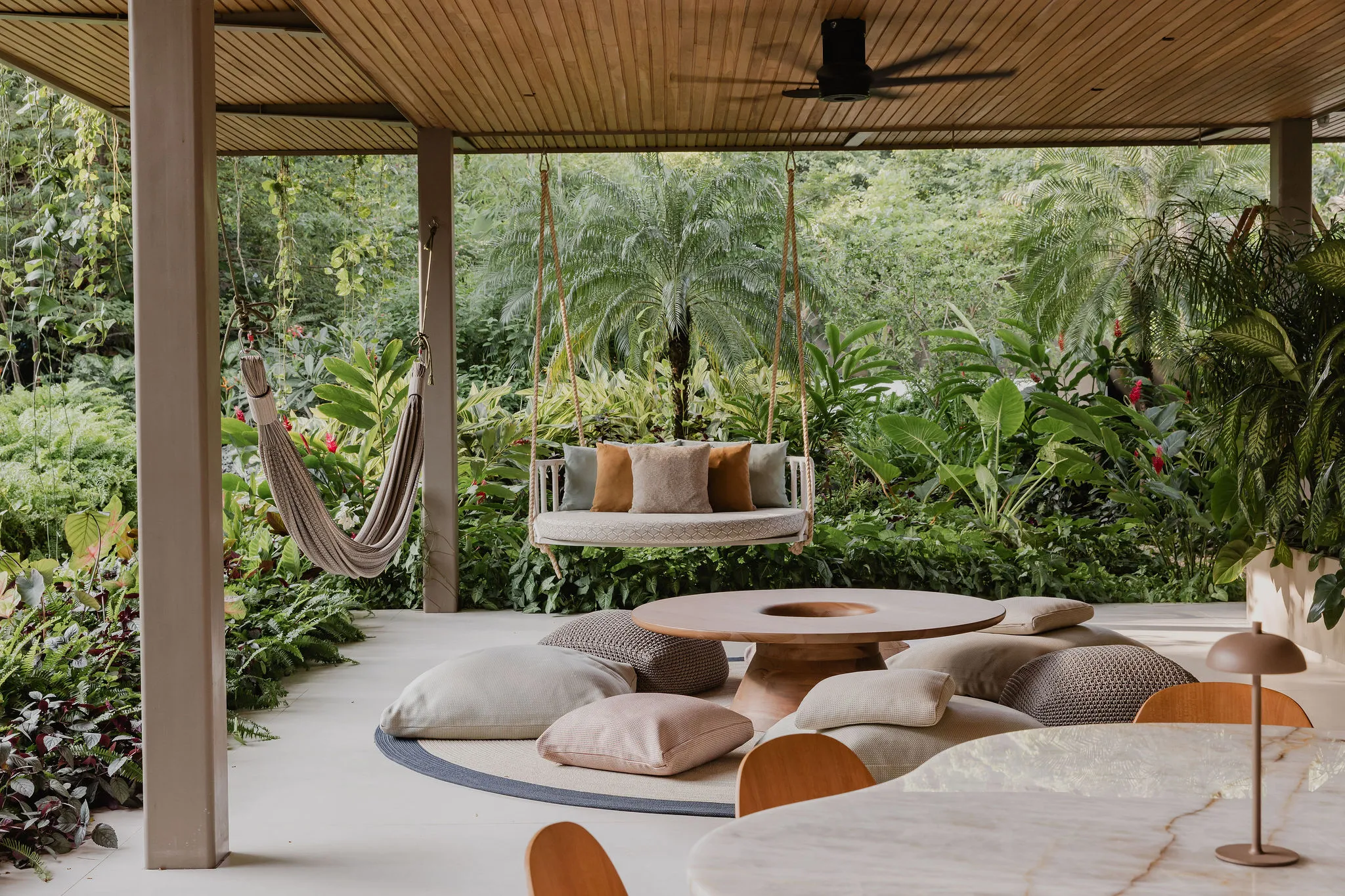 SEN villa outdoor lounge with hammock daybed and floor pillows under wooden ceiling, Nosara