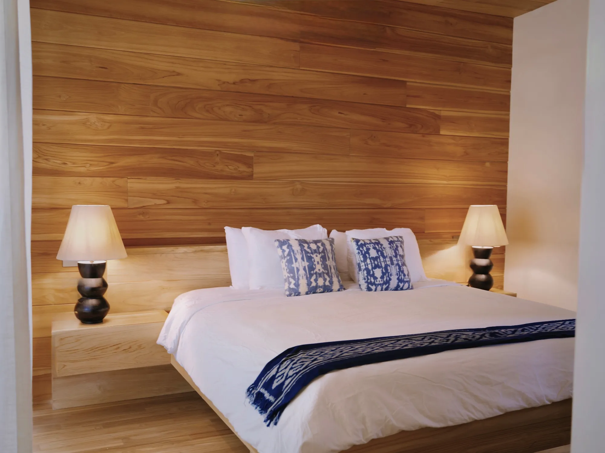 Tres Hermanas villa wood-paneled bedroom with king bed and dual lamps, Playa Guiones Nosara