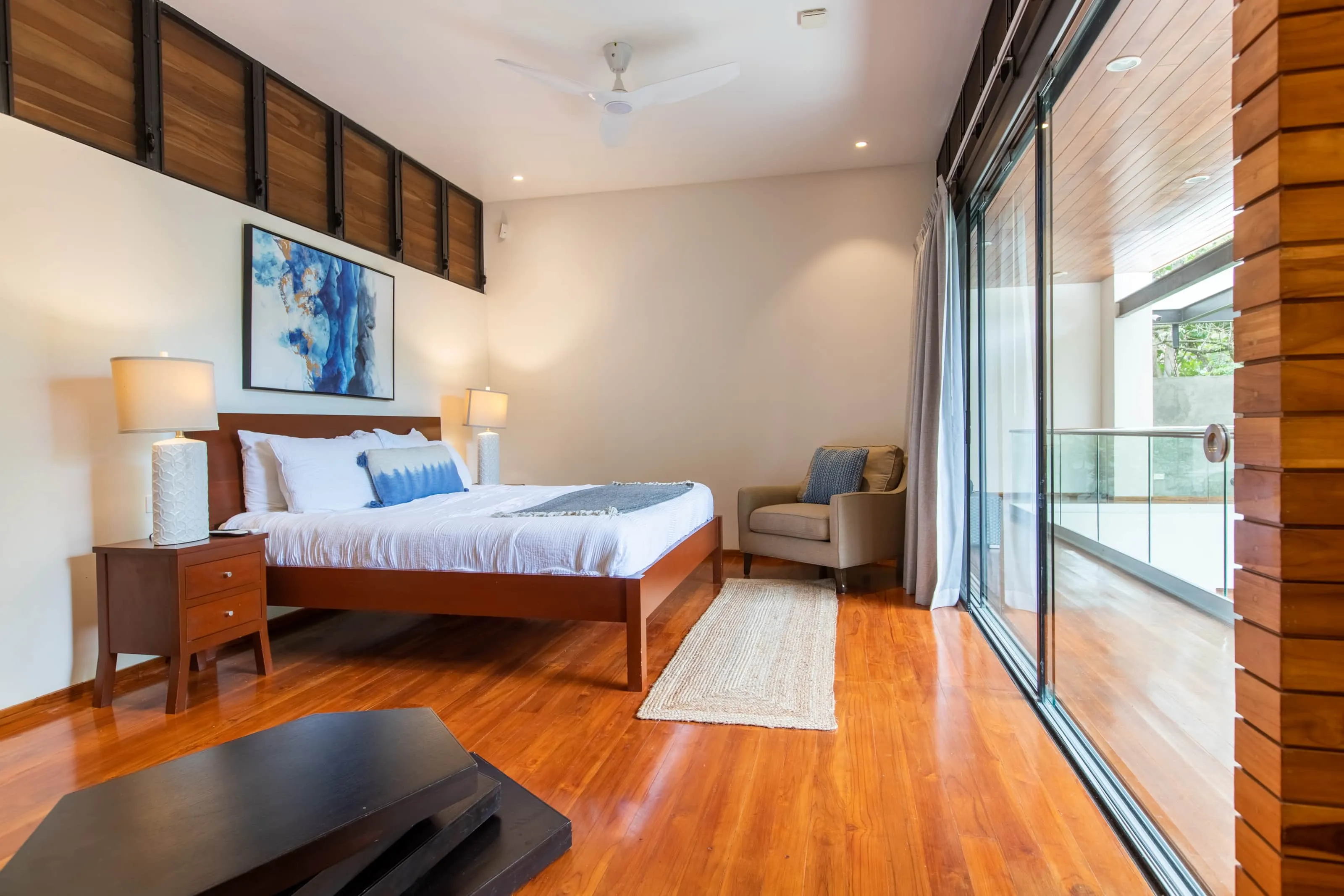 Casa Almendra villa bedroom with rust-orange bedspread and gallery wall, Playa Guiones Nosara