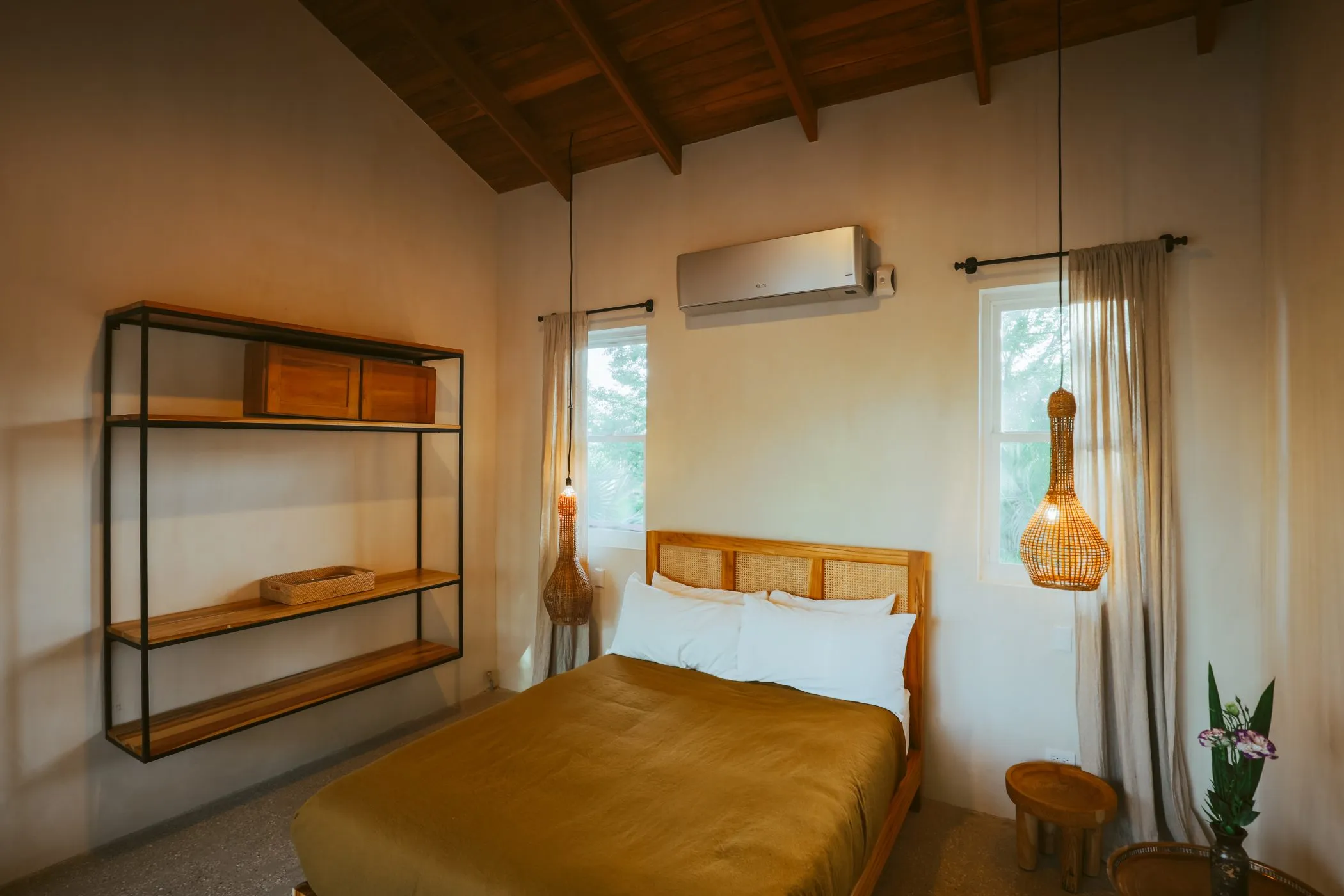 Casa Oceanus villa bedroom with king bed and warm-tone accent wall, Guiones Beach Club Nosara