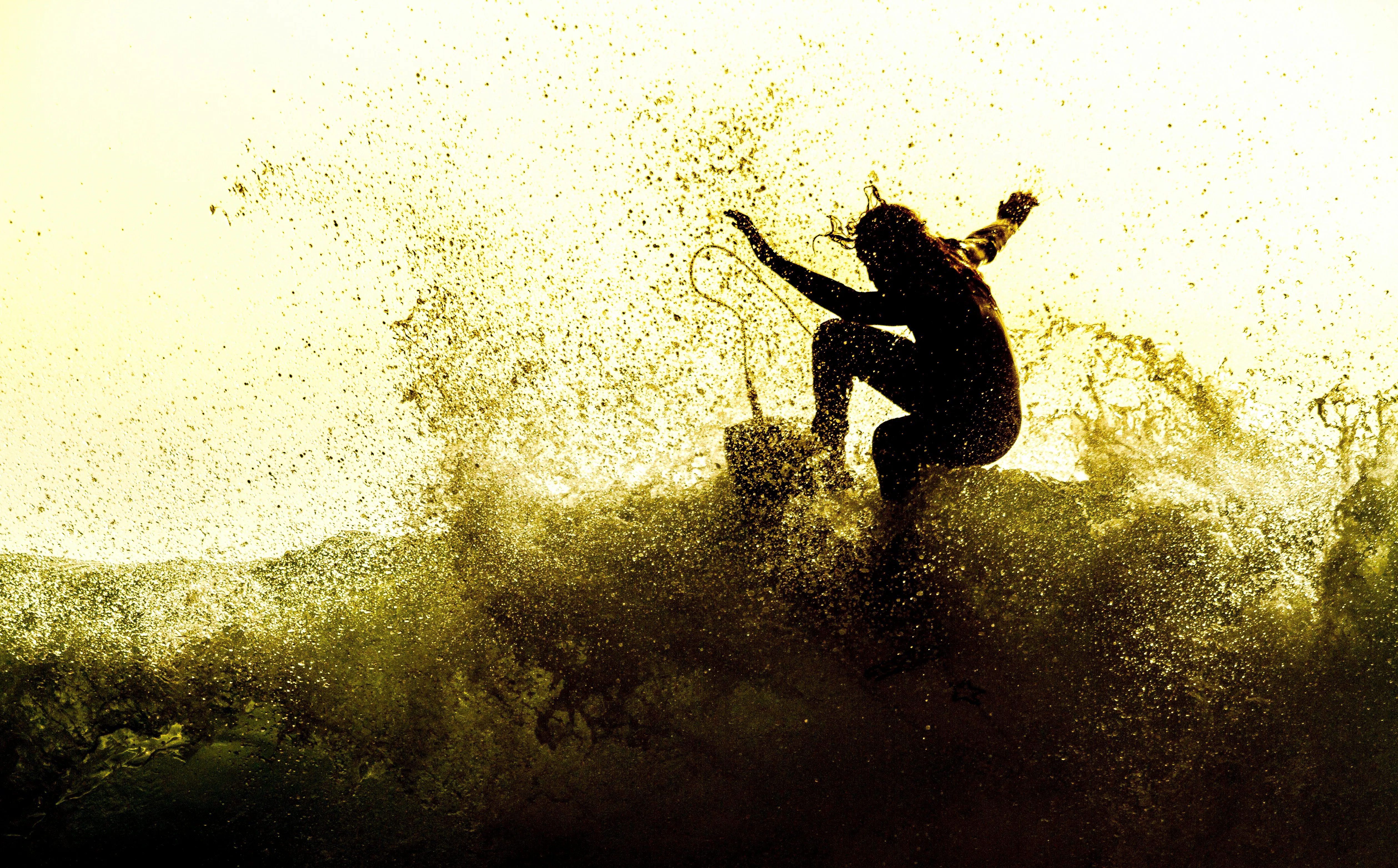 Surfer carving a wave at golden hour with backlit spray at Playa Guiones, Nosara, Costa Rica