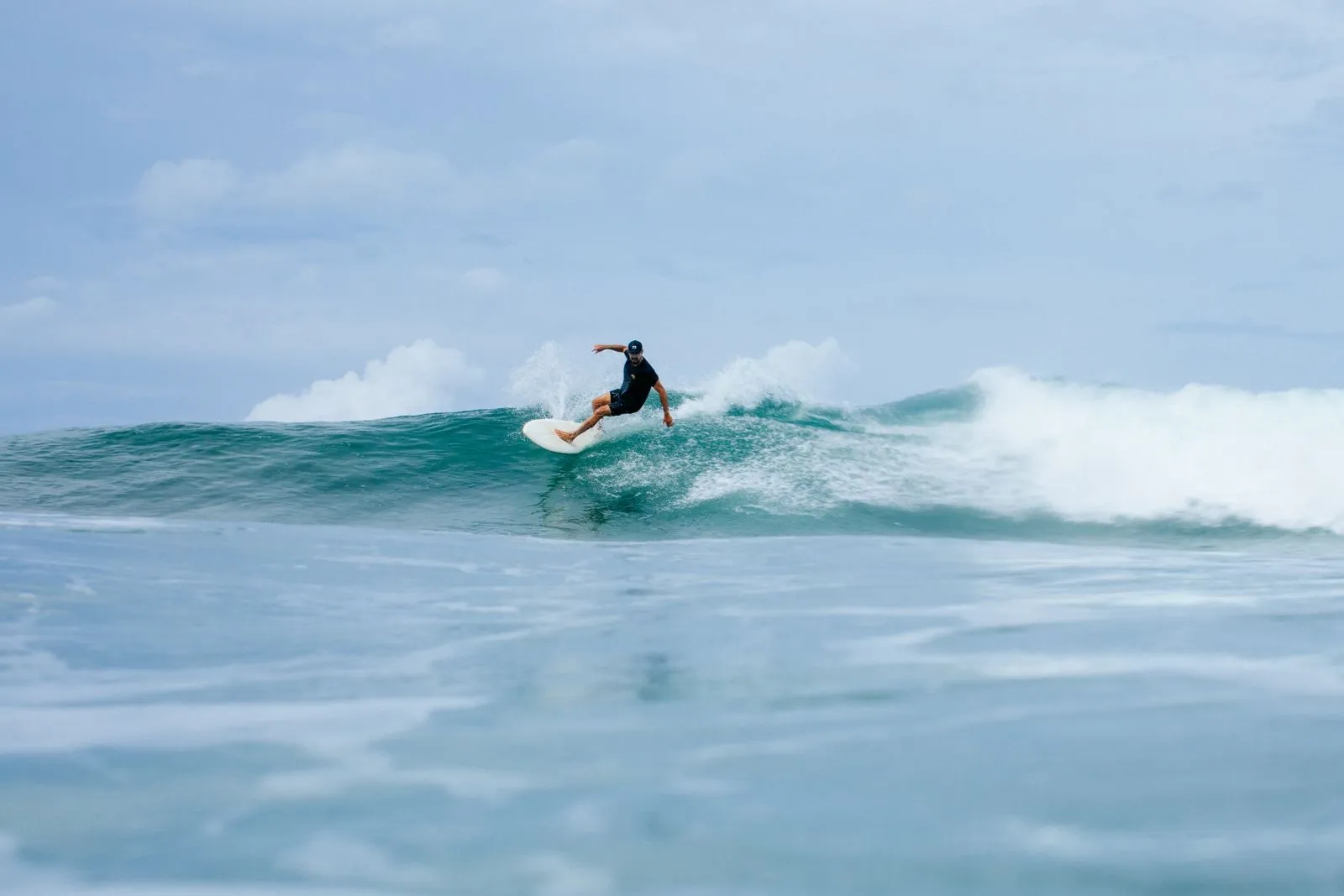 Surfer coming off the top of a clean green wave on an empty peak in Nosara