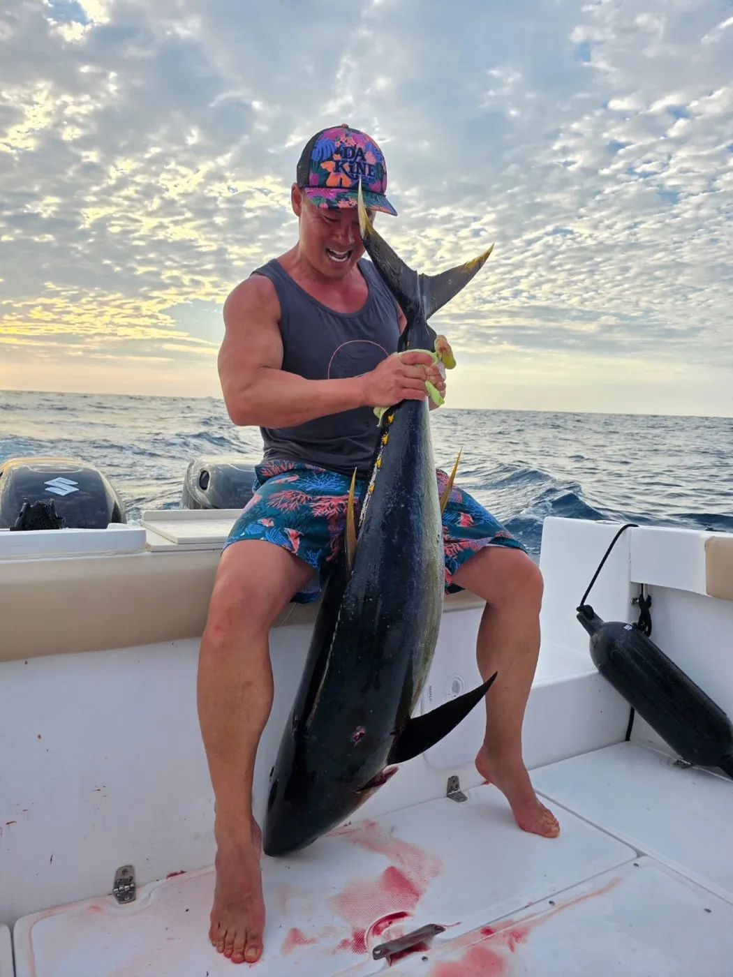 Angler holding a yellowfin tuna aboard the Osprey at sunrise